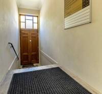 Keskeny lépcsőház létrával és lámpával vezet a faajtóhoz. Irodák.