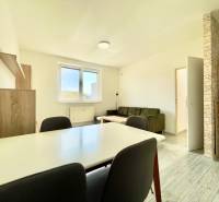 Nappali egy kétszobás lakásban fa mintázatú padlóval, kanapéval és étkezőasztallal.