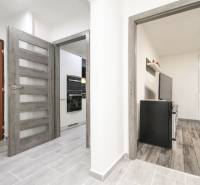 Folyosó egy háromszobás lakásban fa dekorációs padlóval és bejárattal a konyhába.