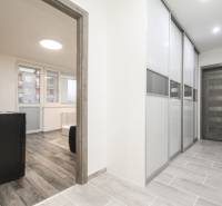 Folyosó tolóajtókkal és fa dekorációjú padlóval egy háromszobás lakásban.