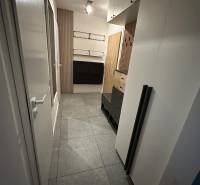 Folyosó egy kétszobás lakásban csempével, szekrényekkel és fa falpanelekkel.