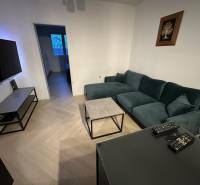 Nappali egy kétszobás lakásban, fa mintás padlóval és kényelmes kanapéval.