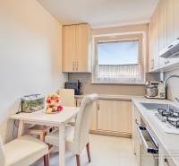 Konyha egy 4 szobás lakásban étkezőasztallal, krémszínű székekkel és konyhabútorral.