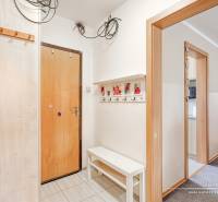 Négy szobás lakás előszobája, fehér falak, fogasok és pad.