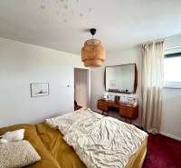 Hálószoba családi házban ággyal, tükörrel és piros szőnyeggel a padlón.