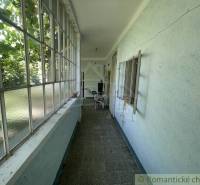 Keskeny üvegezett tér a családi házban, kilátással a kertre.