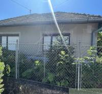 Családi ház Tardoskedden kerítéssel és zölddel, tiszta napos égbolt.