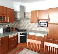 Konyha egy háromszobás lakásban fa dekoros padlóval és konyhabútorral.