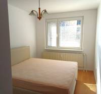 Hálószoba egy háromszobás lakásban, ággyal és fa dekorációjú padlóval.