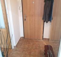 A kétszobás lakás előszobája kerámia padlóval és kabátokkal a fogason.