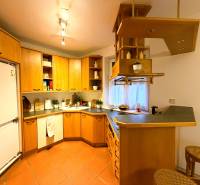 Konyha egy háromszobás lakásban fa szekrényekkel és bárpulttal.