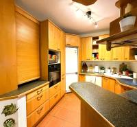 Konyha egy háromszobás lakásban sarok konyhabútorral és fa dekorációjú padlóval.