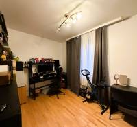 Szoba fa dekoros padlóval, íróasztal, számítógép, szobabicikli, polcok.