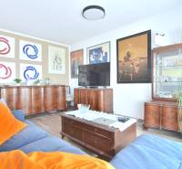 Nappali egy háromszobás lakásban fa bútorokkal, fa dekoros padlóval és képekkel a falakon.