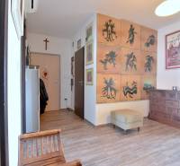 Háromszobás lakás folyosója székekkel, képekkel és fa dekorációjú padlóval.