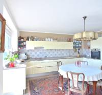 Konyha egy háromszobás lakásban fa bútorokkal, virágokkal és mintás szőnyeggel.