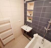 Fürdőszoba a négy szobás lakásban káddal, mosdóval és tároló polcokkal.