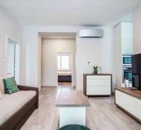 Nappali egy háromszobás lakásban, fa dekor padlóval és kényelmes kanapéval.