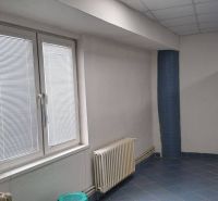 Üzlethelyiség belső tere csempézett padlóval, radiátorral és nagy ablakkal.