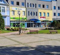 Üzlethelyiségek Homonnában bankokkal és biztosítással, ülőhely, oszlopnak támasztott kerékpár.