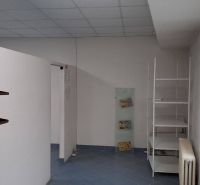 Egy üzlethelyiség belső tere fehér falakkal, polcokkal és kék padlóval.