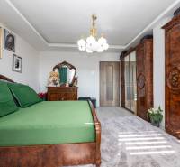 Hálószoba fa bútorokkal és zöld ágyneművel egy családi házban.