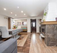 Nappali egy családi házban, fa mintázatú padlóval és kandallóval.