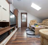 Nappali szoba kanapéval, televízióval és fa dekorációjú padlóval egy családi házban.