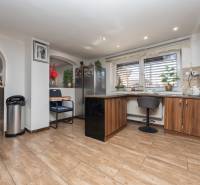 Családi ház konyhája kellemes légkörrel, fa dekoros padlóval, bárszékes ülőhellyel.