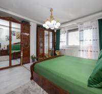 Hálószoba családi házban fa tükrös szekrényekkel és zöld ágyneművel.