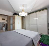 Hálószoba ággyal, fehér szekrénnyel, szőnyegekkel és lámpával egy családi házban.