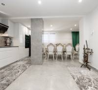 Konyha és étkező székekkel egy családi házban; kőpadló és hagyományos rokka.