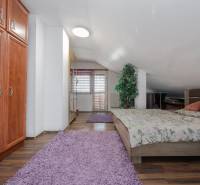 Hálószoba családi házban, ággyal, szekrénnyel és fa dekorációjú padlóval.