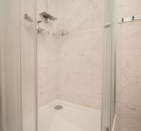 Zuhanyzó fehér márvány csempékkel a fürdőszobában egy háromszobás lakásban.