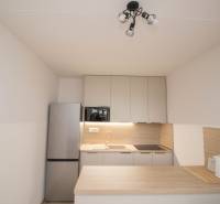 Konyha egy 3-szobás lakásban konyhabútorral, hűtőszekrénnyel és főzőlappal.