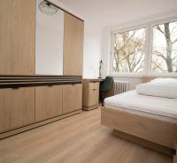 Hálószoba egy háromszobás lakásban ággyal, szekrénnyel és fa dekorációjú padlóval.