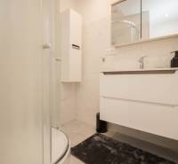 Fürdőszoba egy háromszobás lakásban, modern zuhanyzóval és fehér bútorokkal.