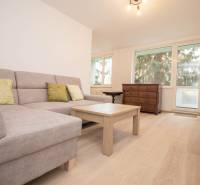 Nappali kanapéval, asztallal és fa dekor padlóval egy háromszobás lakásban.