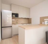 Konyha egy 3 szobás lakásban fa dekor padlóval és modern készülékekkel.