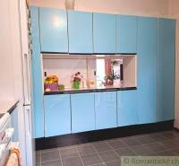 Konyha egy családi házban kék szekrényekkel és fehér készülékekkel.