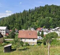 Családi ház Liptovské Revúcéban, zölddel körülvéve és további házakkal az erdő hátterében.
