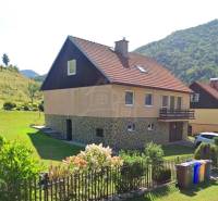 Családi ház Liptovské Revúcéban piros tetővel, kerttel és virágos kerítéssel.