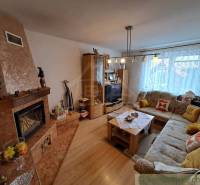 Nappali egy családi házban kandallóval, kanapéval és fa dekoros padlóval.