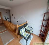 Családi ház belső tere lépcsővel, székekkel és fa dekorációjú padlóval.