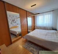 Hálószoba családi házban tükrös szekrényekkel és fa dekoros padlóval.