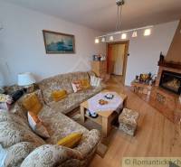 Nappali egy családi házban hímzett kanapéval, fülkés főzőfülke, hangulatos belső tér.