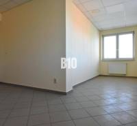 Svetes helyiség, világos falak, ablak és padlóburkolat az irodában.