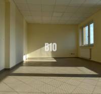 Svetlá prázdna miestnosť a kancelárie s oknom a radiátorom, béžové steny.