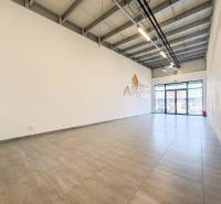 Kereskedelmi helyiségek belső tere nagy formátumú ablakokkal és világos padlóval.