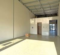 Tágas üzlethelyiség magas mennyezettel és betonpadlóval.